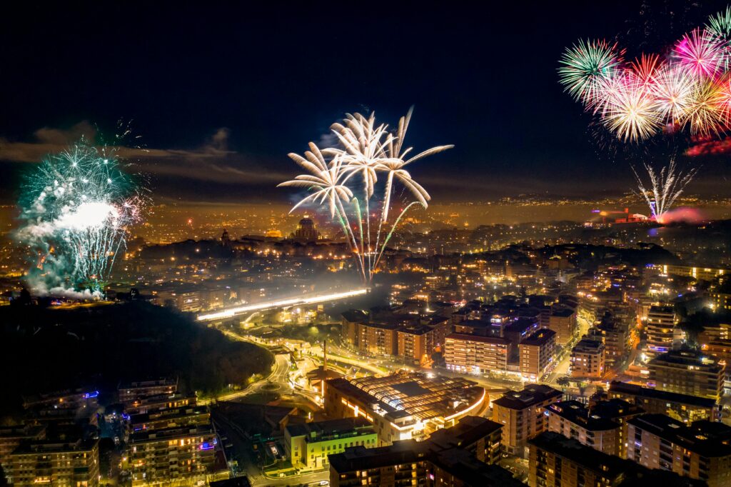 Stunning night aerial shot of Rome's illuminated skyline, celebrating with vibrant fireworks.